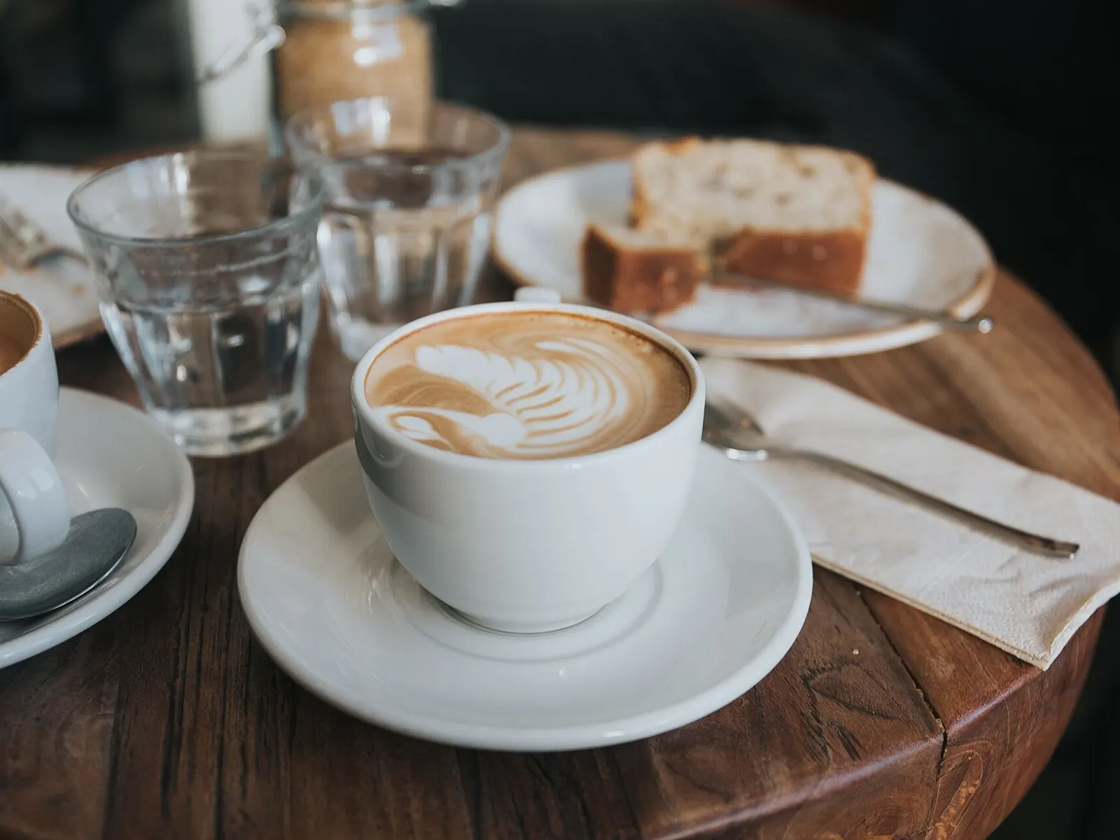 Cappuccino z latte art i kawałek ciasta na stoliku kawiarni