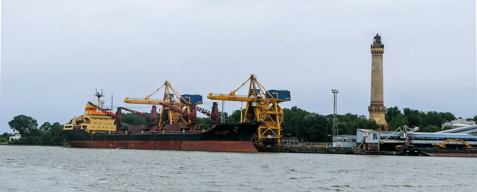 Statek przy nabrzeżu portowym i latarnia morska
